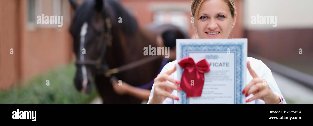 Veterinario donna in possesso di certificato di formazione su sfondo cavallo Foto Stock