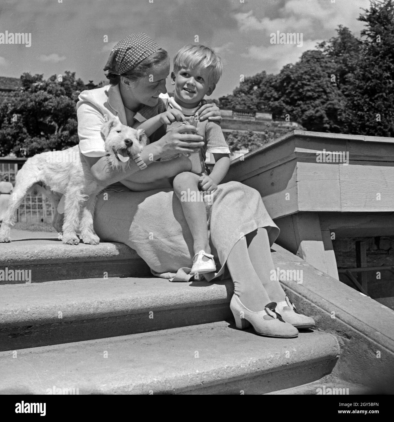 Eine junge Frau und ein kleiner Junge mit seinem Foxterrier auf der Treppe von Schlo Sanssouci in Potsdam bei Berlin, Deutschland 1930 Jahre. Una giovane donna, un ragazzino e il suo cane da compagnia sul perrone del castello di Sanssouce a Potsdam, vicino a Berlino, in Germania, anni trenta. Foto Stock