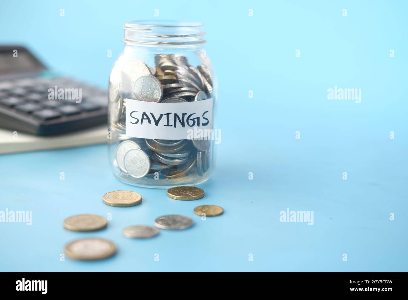 vasetto di risparmio monete e calcolatrice sul tavolo Foto Stock