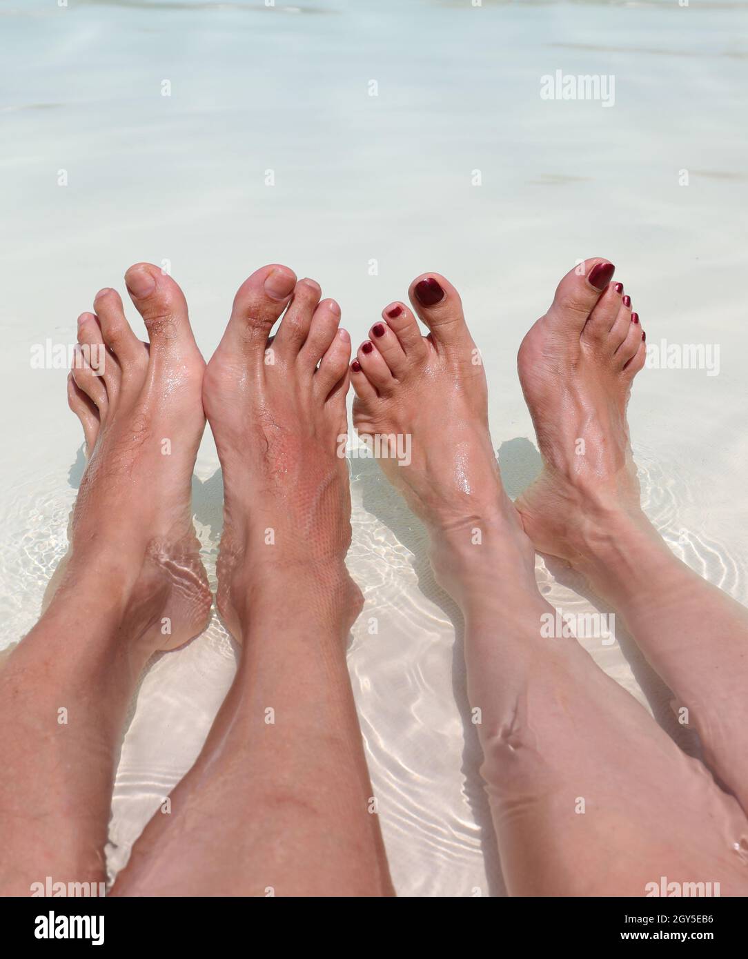 I piedi di marito e di moglie in luna di miele si rilassano nella piscina del Resort Foto Stock