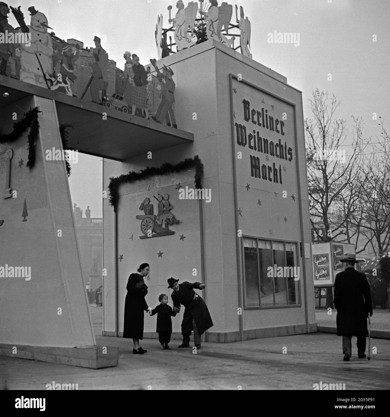 Ein kleiner Junge mit seinen Eltern am Eingang zum Berliner Weihnachtsmarkt, Deutschland 1930er Jahre. Un ragazzino con i suoi genitori all'ingresso della Berlino Mercatini di Natale, Germania 1930s. Foto Stock