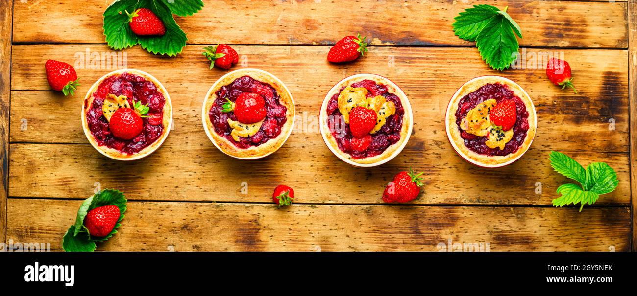 Deliziosi tartlet con marmellata di frutti di bosco.Cake con fragole su rustico sfondo di legno Foto Stock