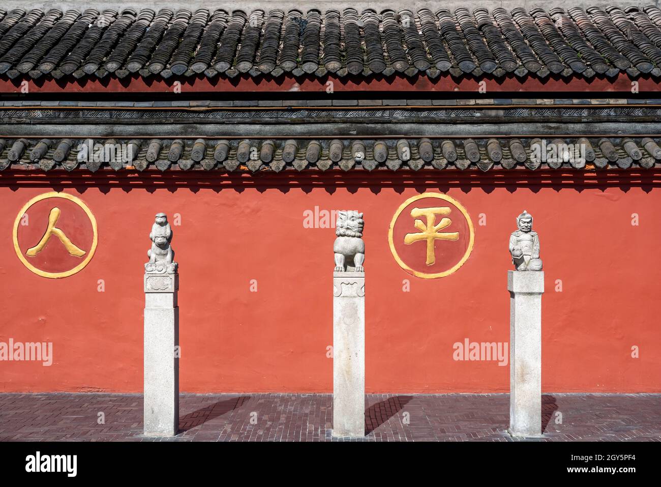 Chengdu, provincia di Sichuan, Cina - 28 settembre 2021 : tre statue di fronte alla parete rossa circostante del monastero buddista di Wenshu con i caratteri cinesi - ren ping- significa pace della gente. Foto Stock