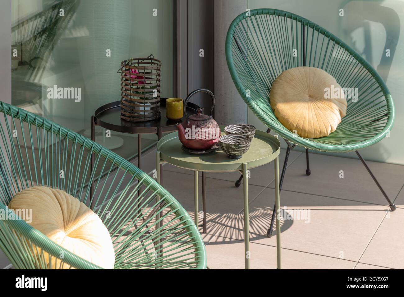 Elegante angolo di una terrazza di una casa moderna con due poltrone e un tè cinese con due tazze. Giornata estiva soleggiata Foto Stock