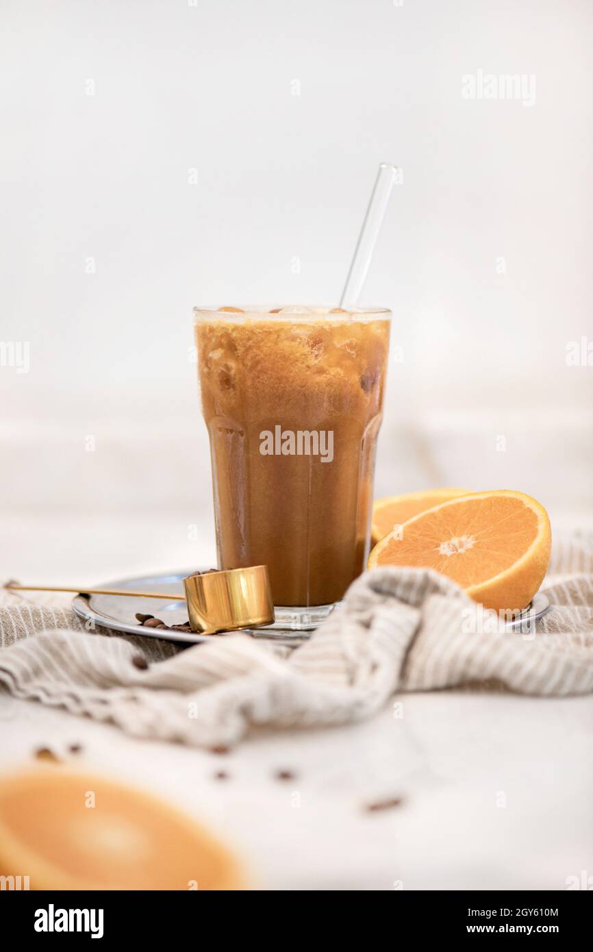 Caffè ghiacciato e succo d'arancia fresco bevanda miscelata con arancio fresco su sfondo bianco, primo piano, fuoco selettivo. Bevanda idilliaca per una pausa Foto Stock