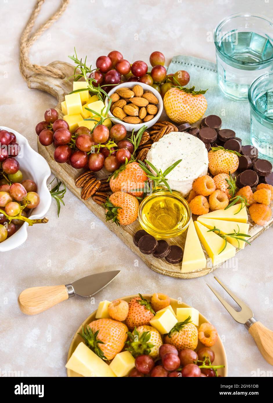 Formaggio a tavola con formaggio, noci, frutta, bacche e cioccolato Foto Stock