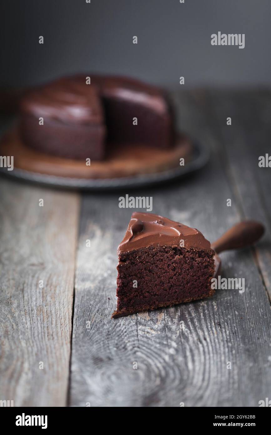 Una fetta di torta al cioccolato glassata su una superficie di legno Foto Stock