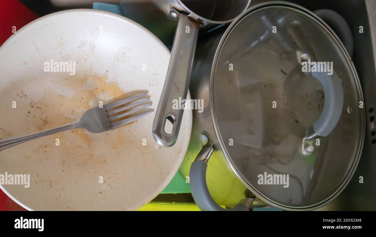 Gli utensili da cucina nel lavabo devono essere lavati. Un mucchio di piatti sporchi nel lavandino della cucina. Gli utensili da cucina hanno bisogno di lavarsi. Concetto di esercitazione Foto Stock