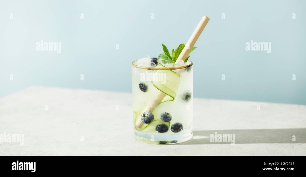 Drink estivi alla moda con cetriolo, menta e mirtillo su sfondo blu cielo Foto Stock
