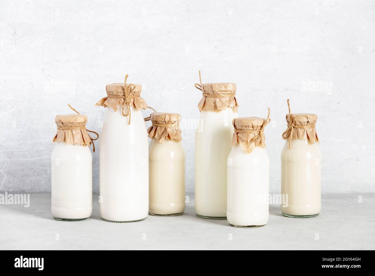 Latte a base di piante vegane non lattiere in bottiglie su sfondo chiaro. Alternativa al latte senza lattosio Foto Stock