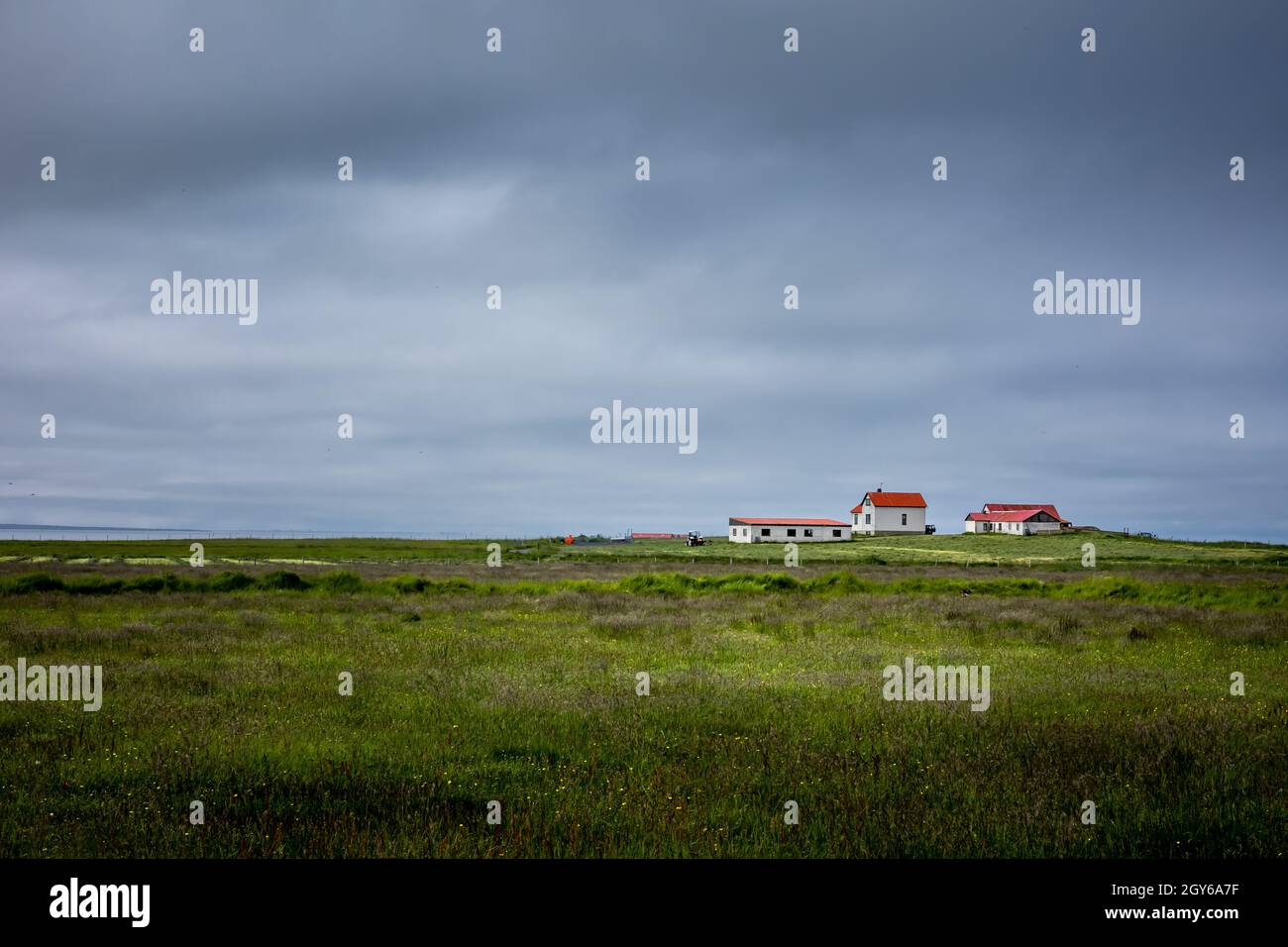 Hafnarfjordur, Islanda - 17 luglio 2021: Un paesaggio della campagna islandese. Piccola chiesa con tetto rosso all'orizzonte. Campi di erba verde, overc Foto Stock