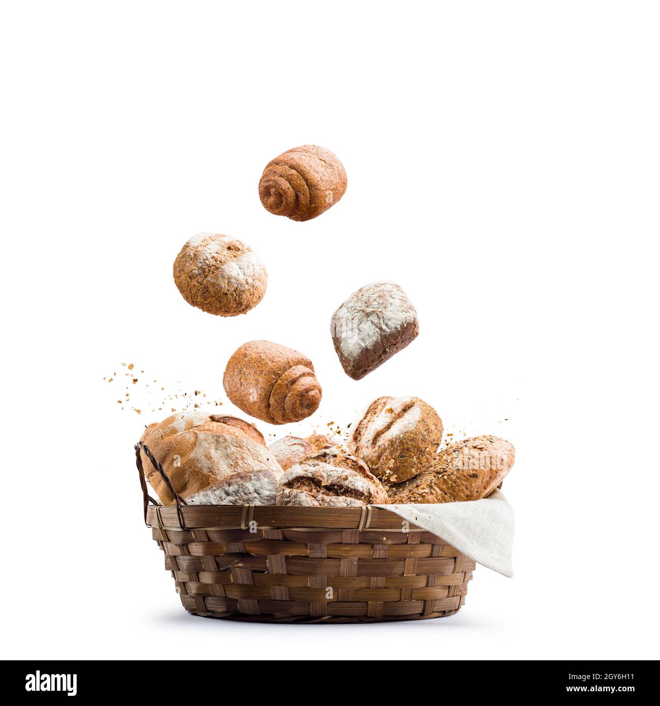 assortimento di pane cotto che cade in un cestino di paglia su sfondo bianco Foto Stock