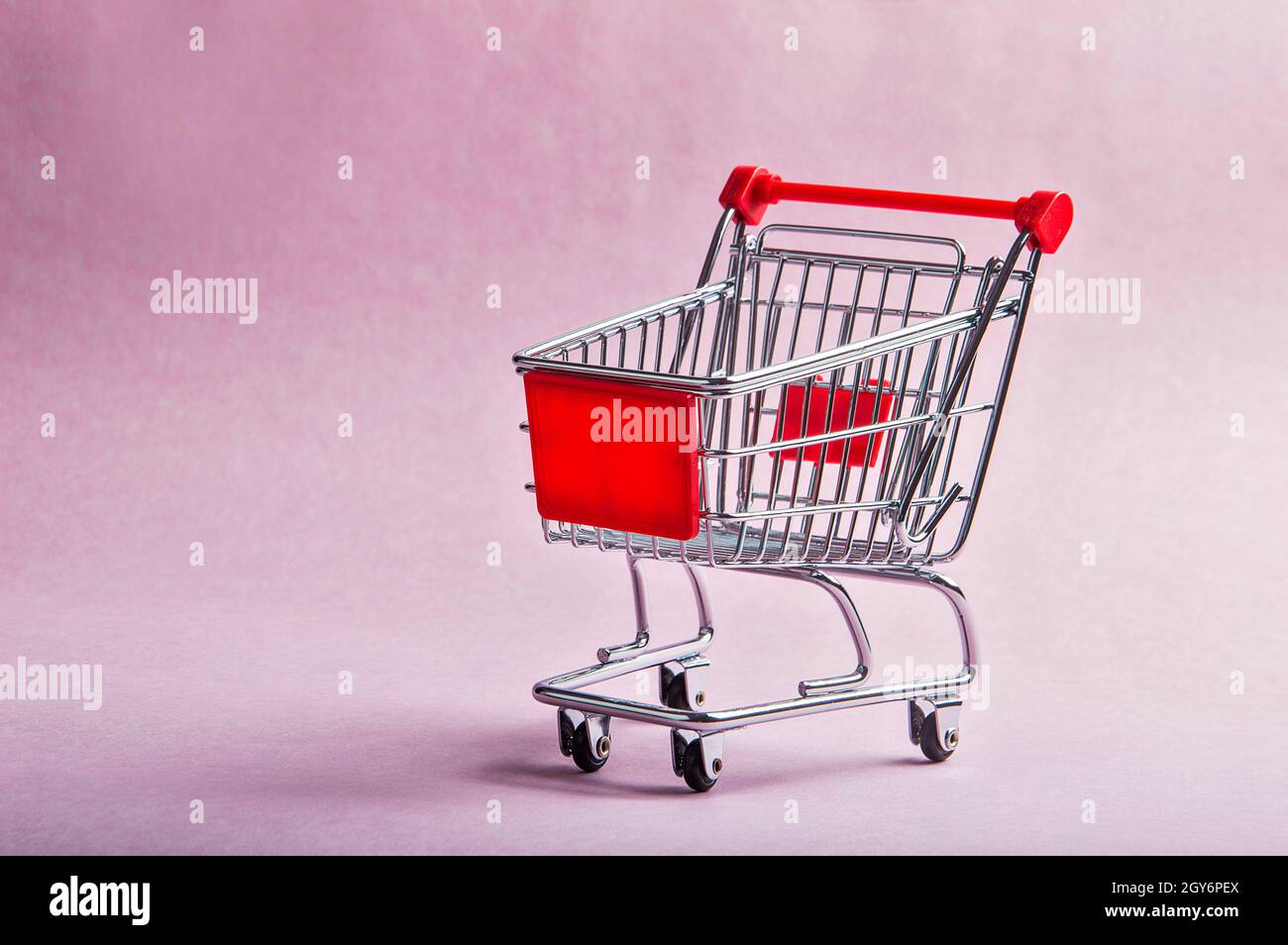 Un carrello della spesa o il trolley su sfondo rosa Foto Stock