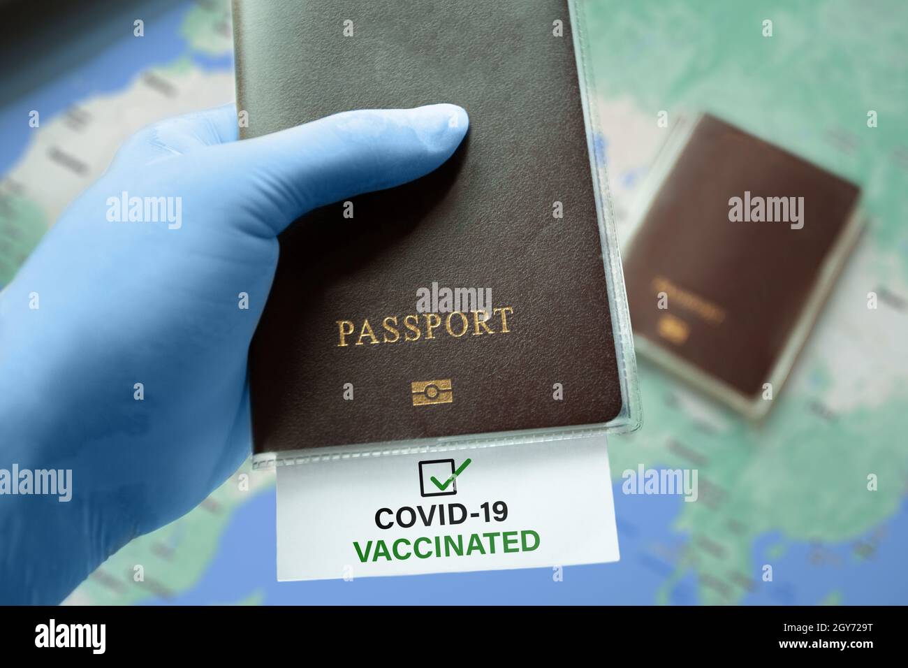 Portare con sé guanti medici che tengono il passaporto con COVID-19 vaccinato nota con segno di spunta sulla mappa. Situazione di focolaio di coronavirus, viaggiando dopo pandemia Foto Stock
