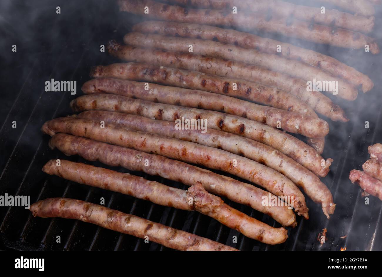 Primo piano cottura salsicce di carne alla griglia, fumatori e brocciatura, vista ad angolo alto Foto Stock