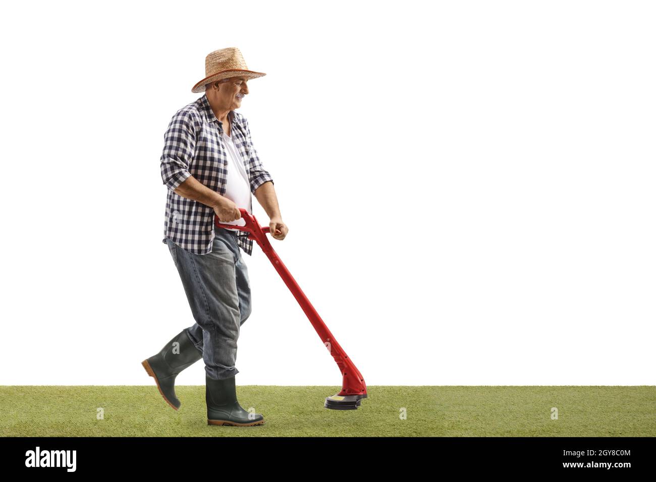 Sparo a tutta lunghezza di un uomo maturo che cammina e rifilatura dell'erba con una macchina tagliatrice isolata su sfondo bianco Foto Stock