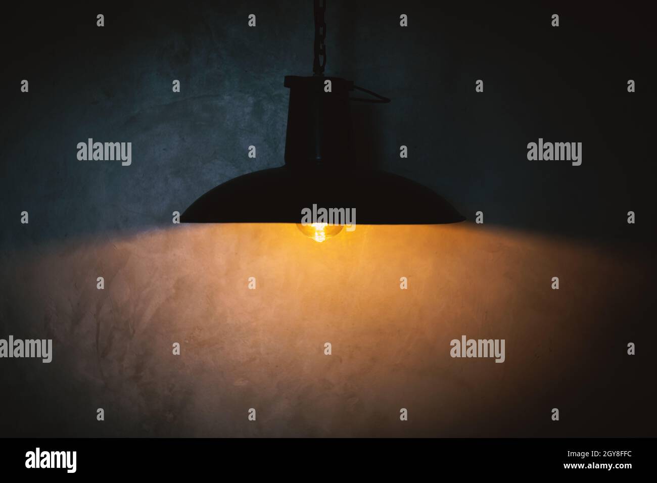 Lampada nera e riflessione di luce gialla su parete di cemento Foto Stock