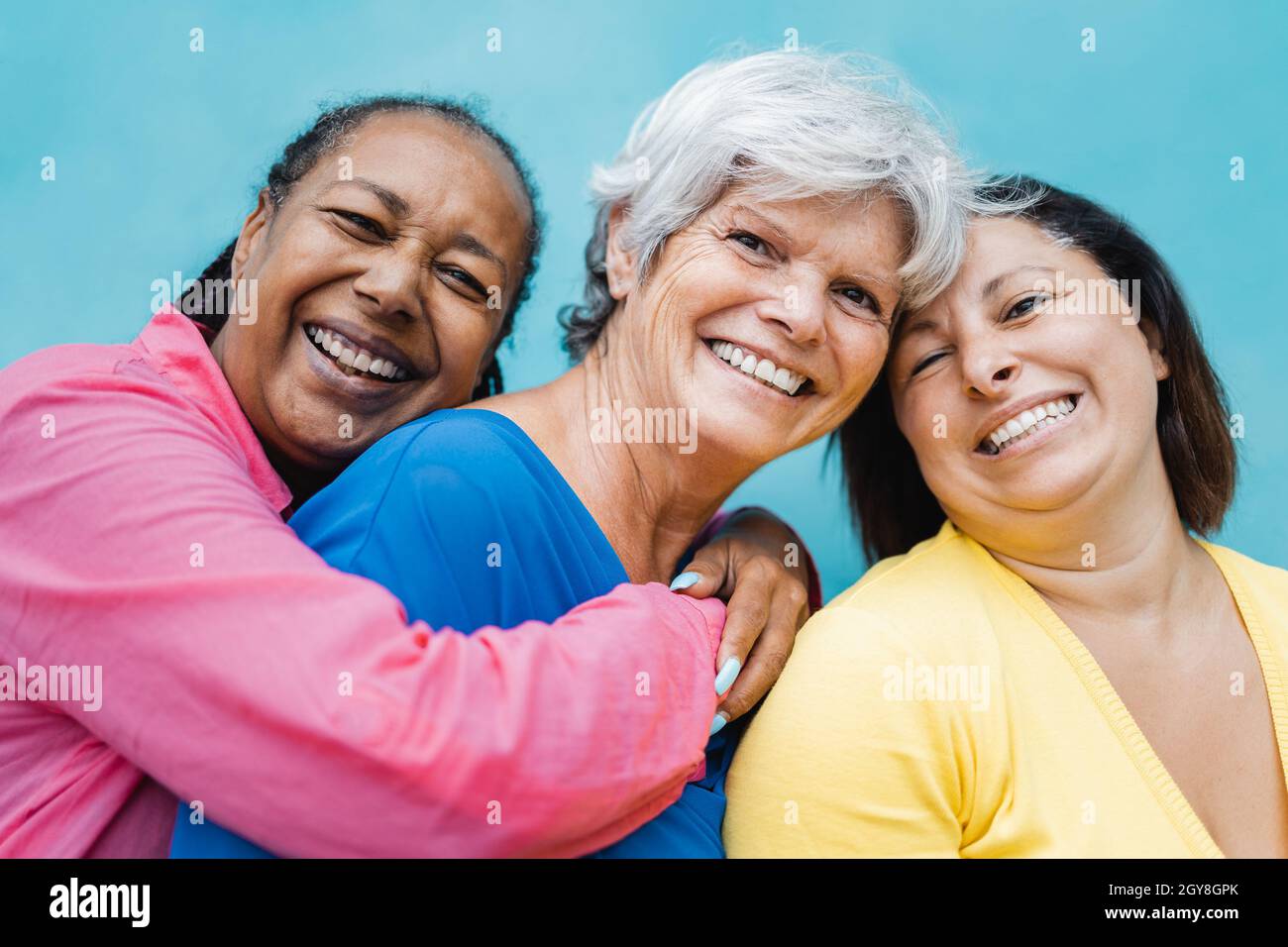 Felice persone anziane diverse abbracciarsi all'aperto - concetto di comunità di amici anziani - Focus sul volto donna centrale Foto Stock