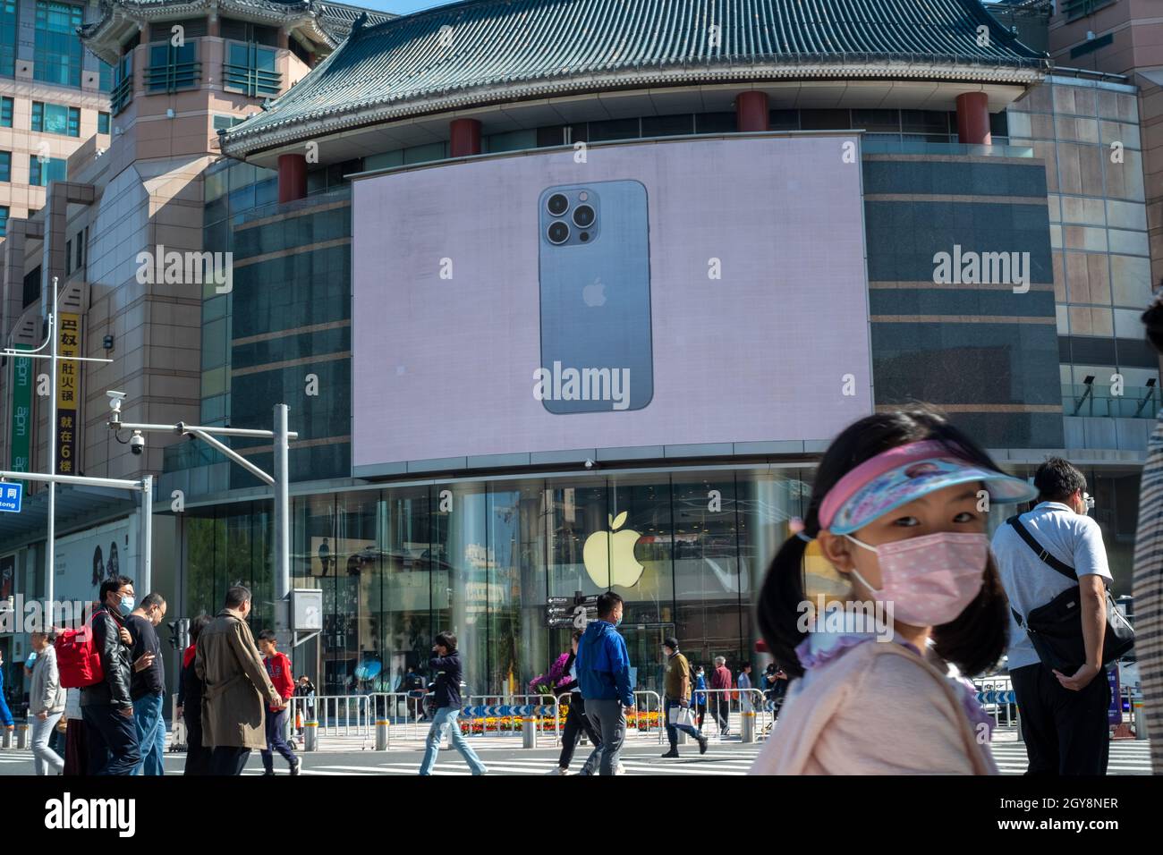 La gente cammina davanti a un negozio di mele a Wangfujing con la serie di pubblicità iPhone 13 su un grande schermo a Pechino, Cina. 07 ottobre 2021 Foto Stock