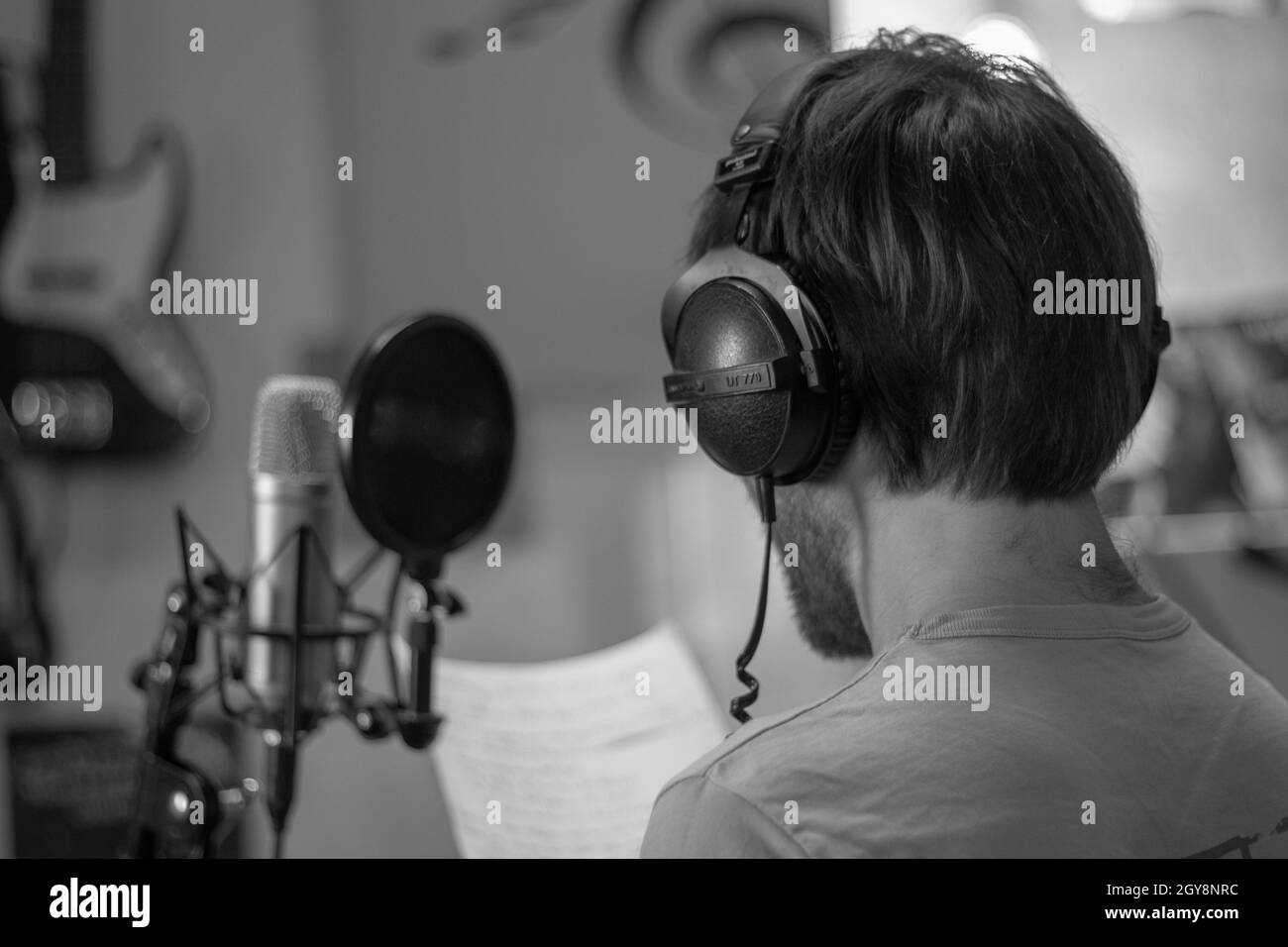 Cantante in studio di fronte al grande diaframma con cuffie. Foto Stock