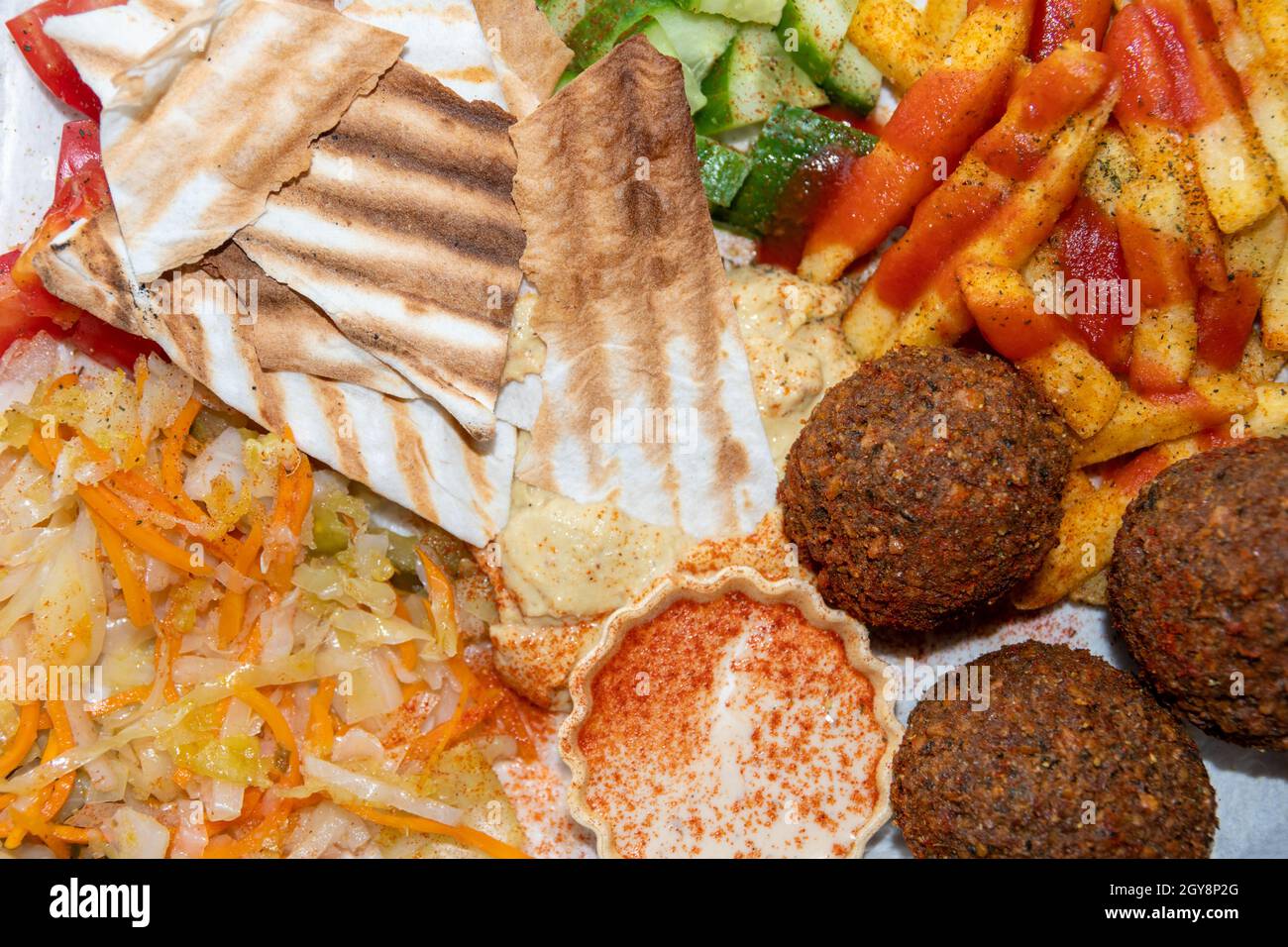 Cucina mediorientale o araba. Primo piano di falafel, hummus, tabbouleh, pita pane e verdure, vista dall'alto. Tacos vegani. Cibo sano vegetariano. Foto Stock