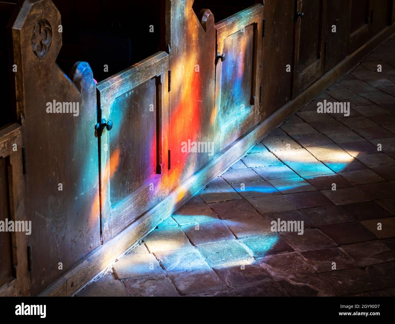 La luce del sole attraverso una vetrata che brilla sulle cialde in una chiesa di Suffolk, Regno Unito. Foto Stock
