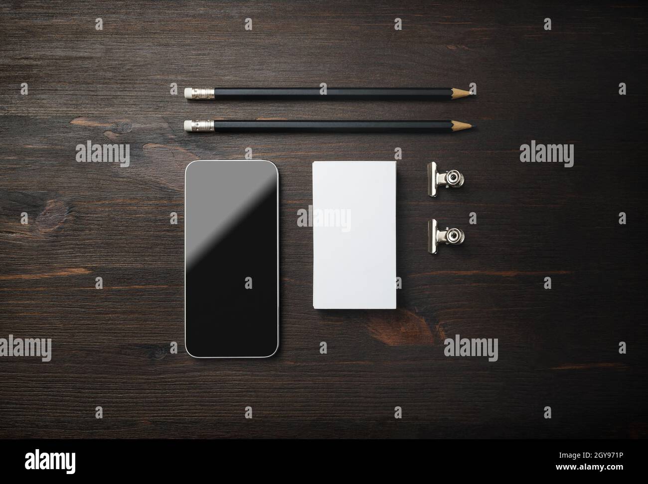 Smartphone, biglietto da visita e matite. Cancelleria vuota su sfondo di legno. Modello ID. Mockup per l'identità di branding per i progettisti. Vista dall'alto. F Foto Stock