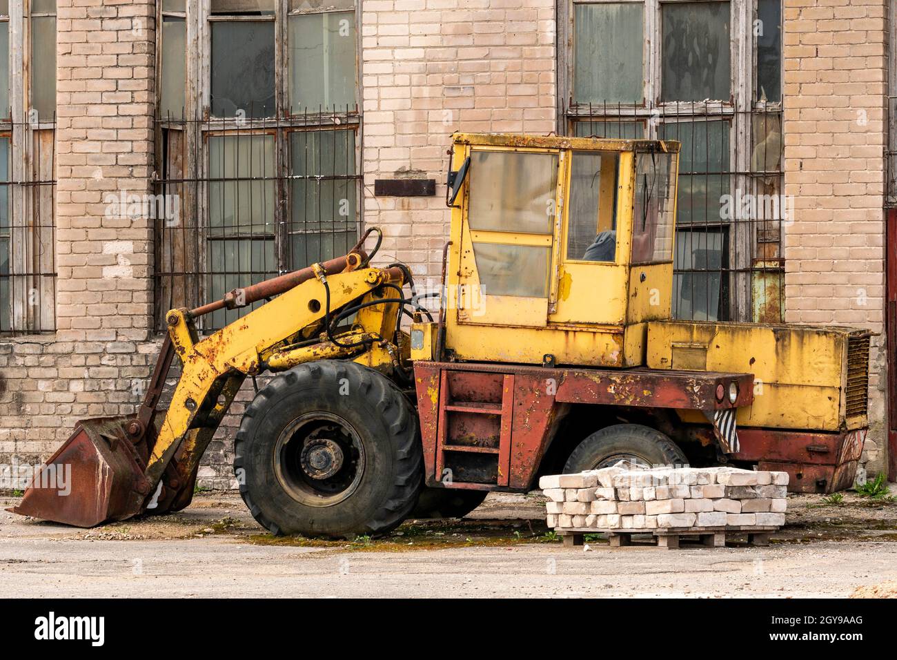 Vecchio bulldozer giallo rotto nel cortile di fabbrica abbandonato Foto Stock