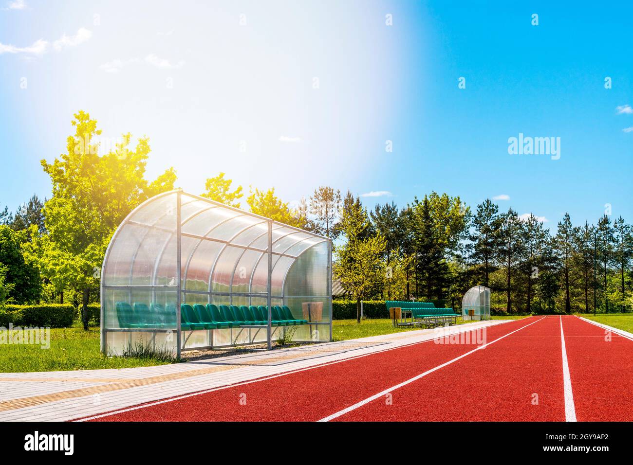 Vista prospettica di uno stadio all'aperto con piste da running rosse, sedie in plastica, infrastrutture per attività sportive Foto Stock
