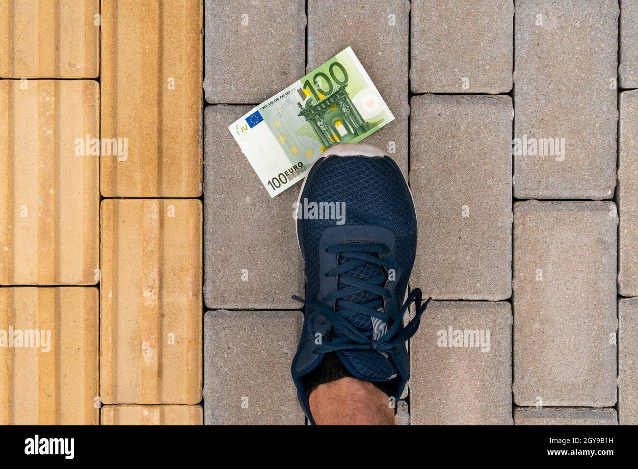 Soldi che giacciono a terra, scarpe che vi salpano. Euro persi su una strada. Foto Stock