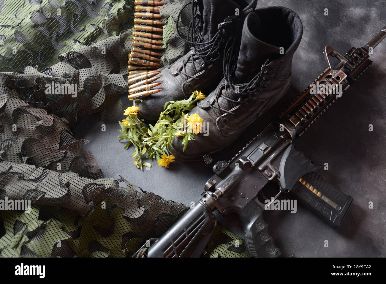 Giorno della memoria israeliana Yom Ha'zikaron. Set militare dell'esercito , stivali da soldato in pelle nera, armi, munizioni e fiori gialli . Concetto di guerra e pace Foto Stock