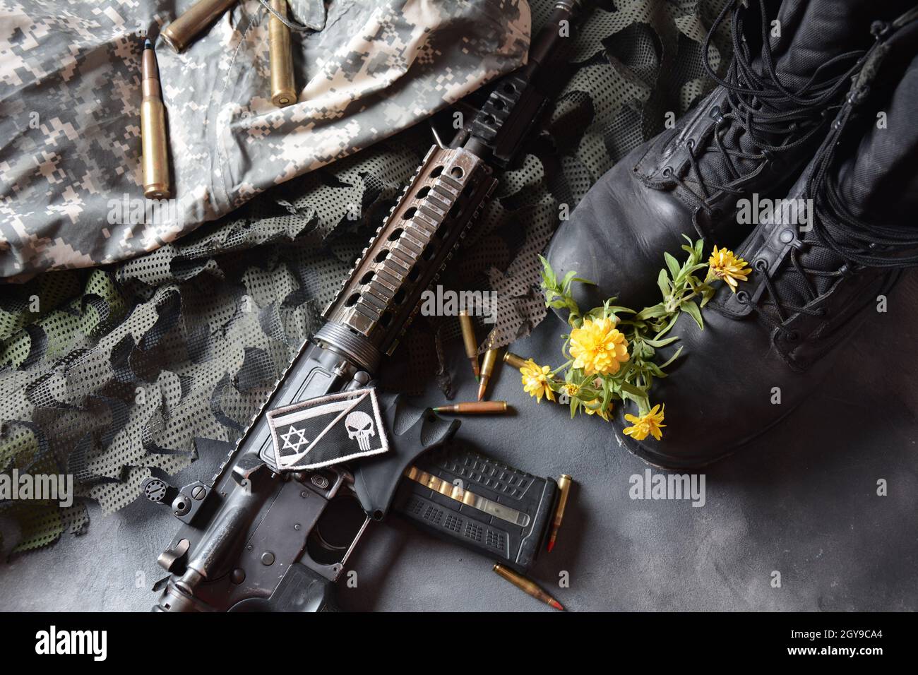 Giorno della memoria israeliana Yom Ha'zikaron. Set militare dell'esercito , stivali da soldato in pelle nera, armi, munizioni e fiori gialli . Concetto di guerra e pace Foto Stock