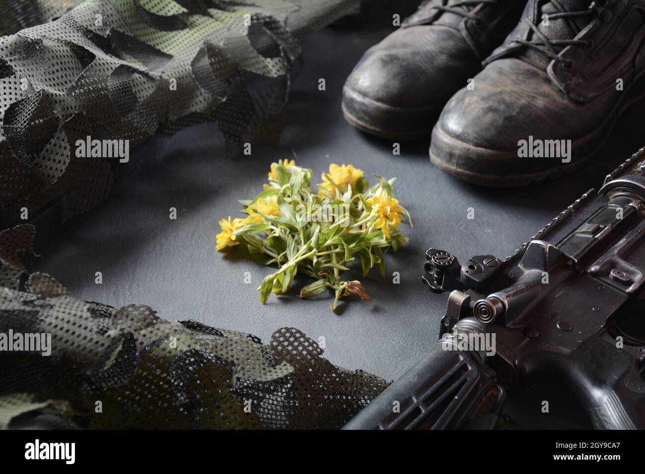 Giorno della memoria israeliana Yom Ha'zikaron. Set militare dell'esercito , stivali da soldato in pelle nera, armi, munizioni e fiori gialli . Concetto di guerra e pace Foto Stock