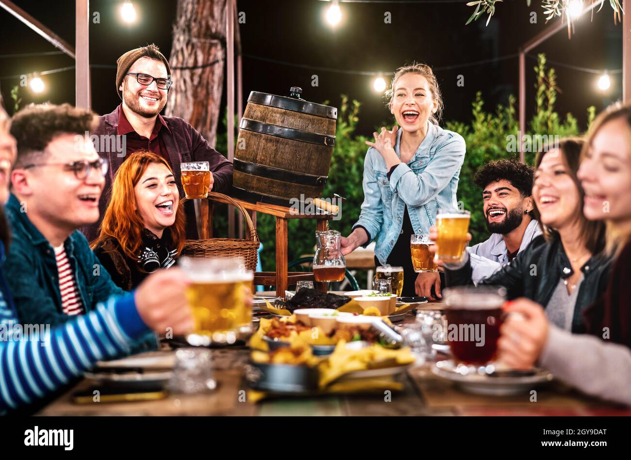 Uomini e donne felici che si divertono a bere fuori al birreria all'aperto - concetto di stile di vita di riunione sociale sui giovani che godono il tempo di ritrovo insieme Foto Stock