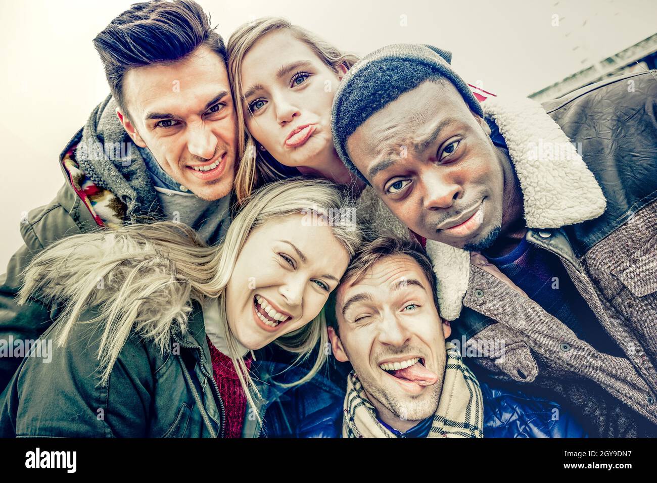 I migliori amici che prendono selfie all'aperto sui vestiti invernali autunnali - concetto felice della gioventù con gente multirazziale che si diverte insieme Foto Stock