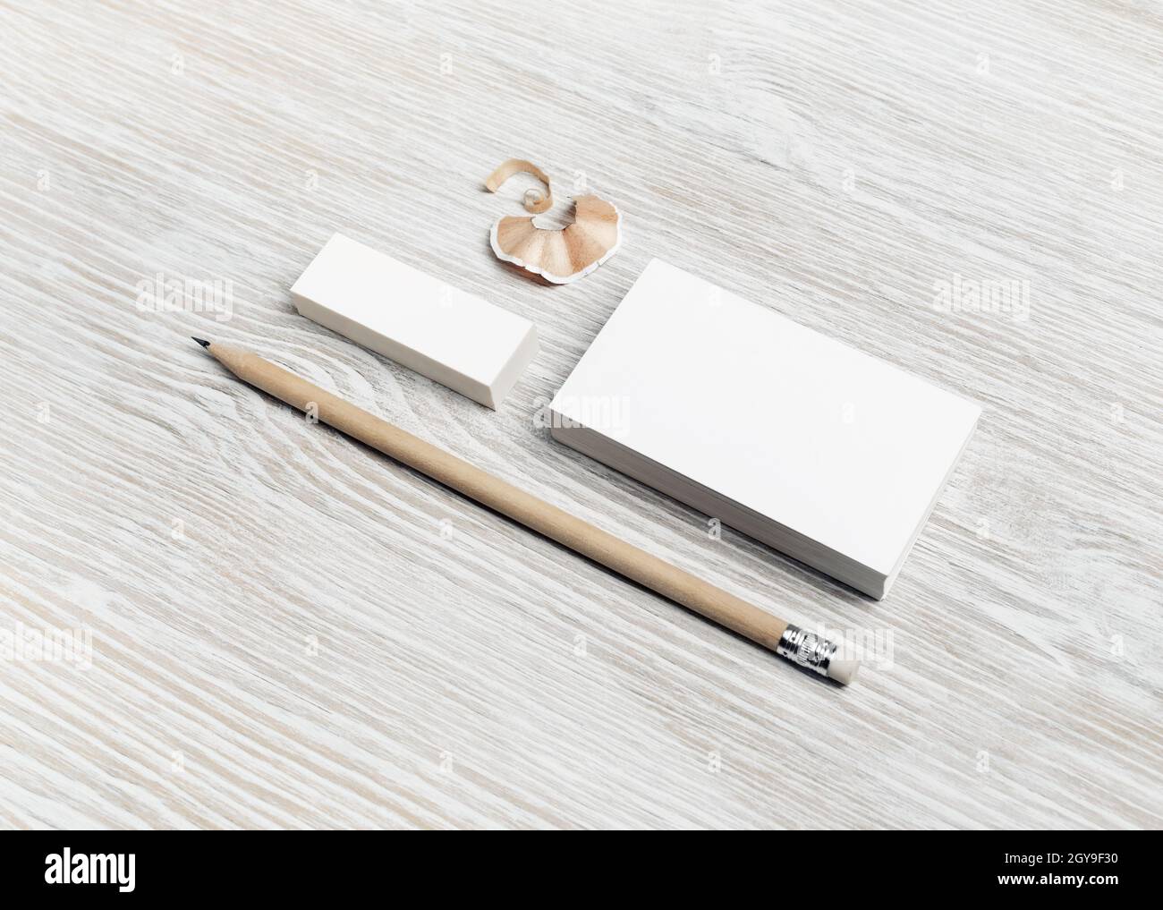 Mockup ID marchio. Biglietto da visita bianco vuoto, matita e gomma su sfondo di legno chiaro. Foto Stock
