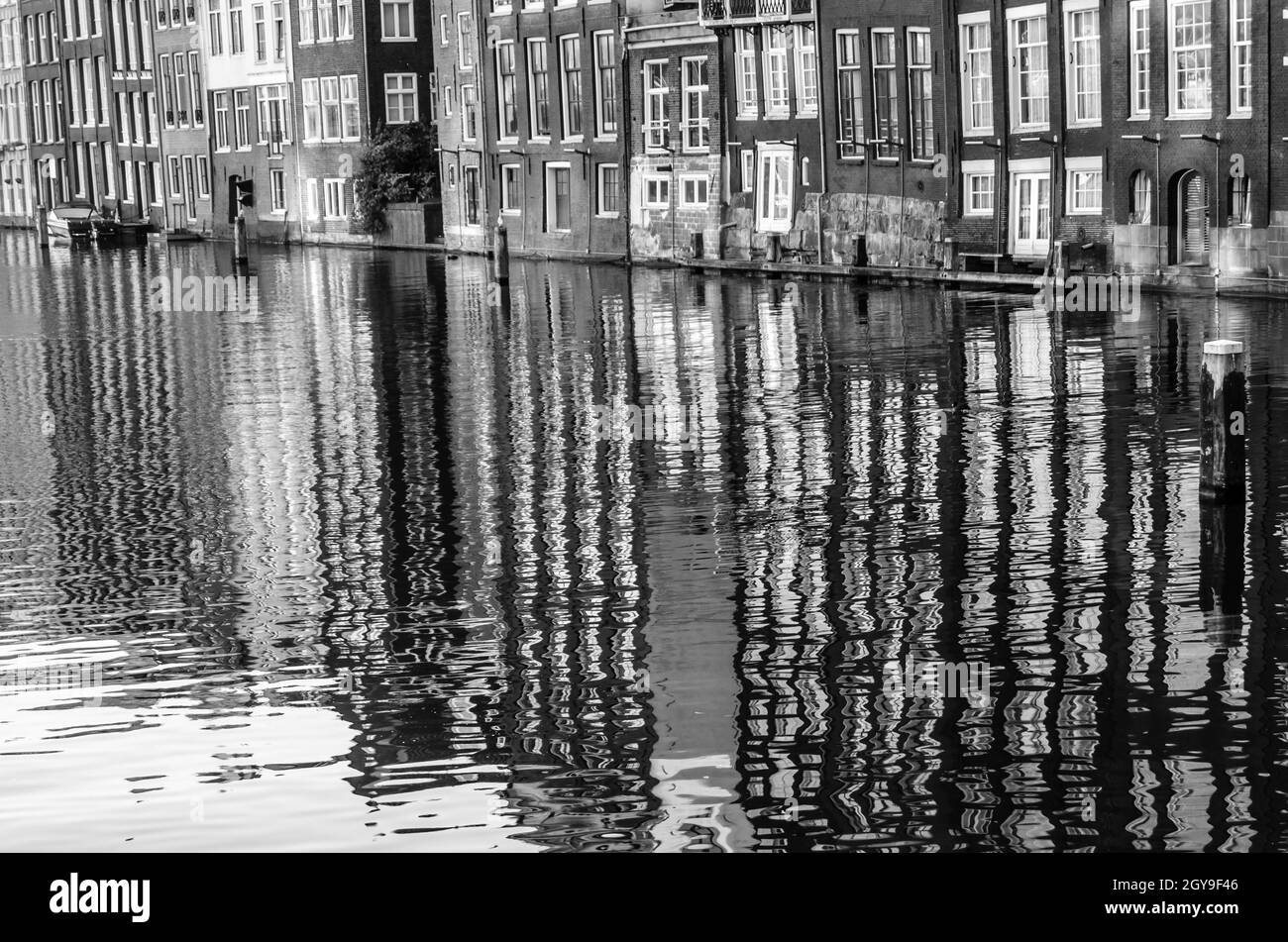 Case lungo il canale e il loro riflesso in acqua ad Amsterdam, Paesi Bassi. Immagine in bianco e nero Foto Stock