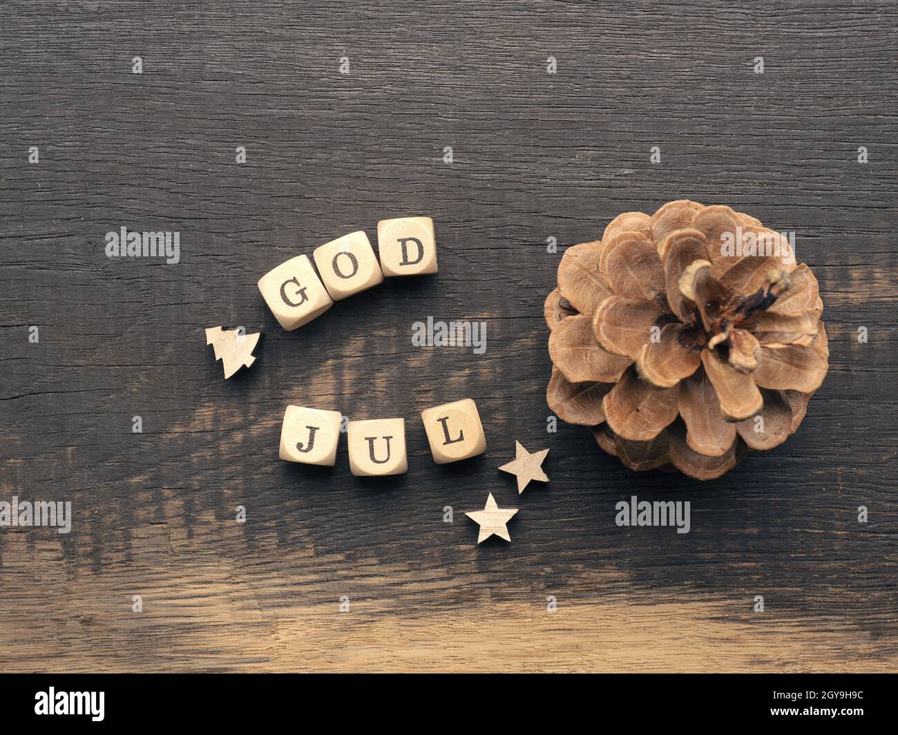 Cono di pino e dadi di legno con le parole Dio lug, scandinavo buon Natale Foto Stock