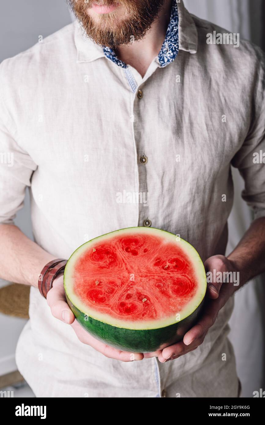 Uomo portato in camicia di lino con metà di cocomero maturo in mano Foto Stock