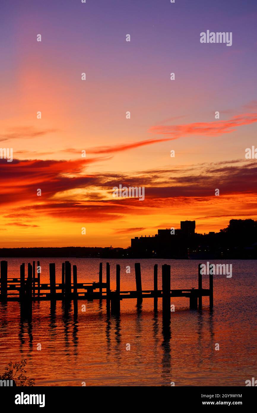 Alba rossa dorata con banchine sedute in un'insenatura con ondate d'acqua Foto Stock