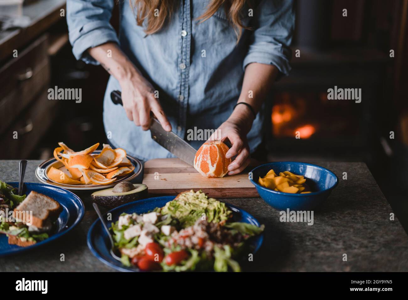 Donna fette di arancio per pranzo sul tagliere all'interno della cabina Foto Stock