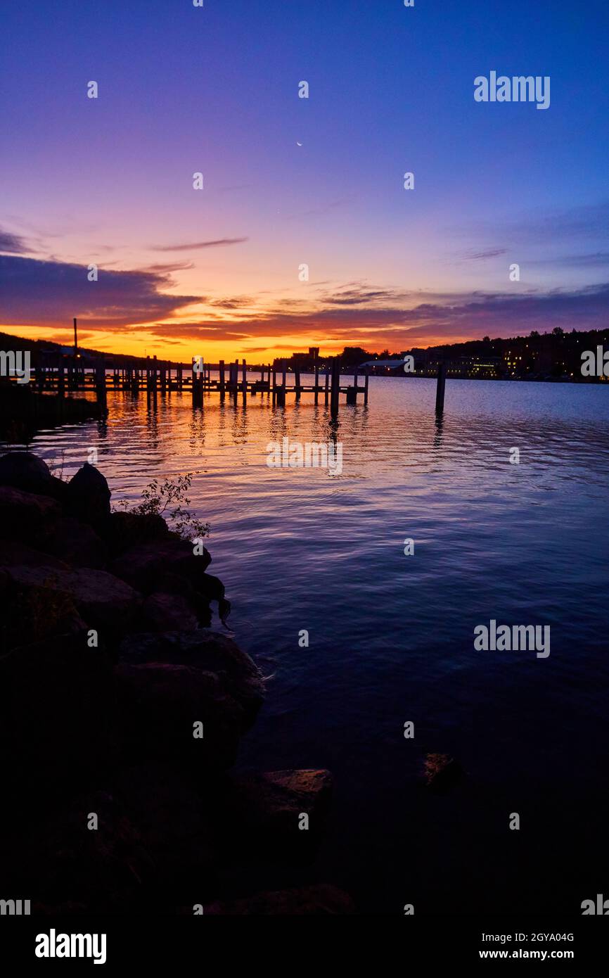 Alba presto vicino a banchine con accenni di rosa oro e viola contro una profonda riviva blu e una silhouette dei banchine Foto Stock