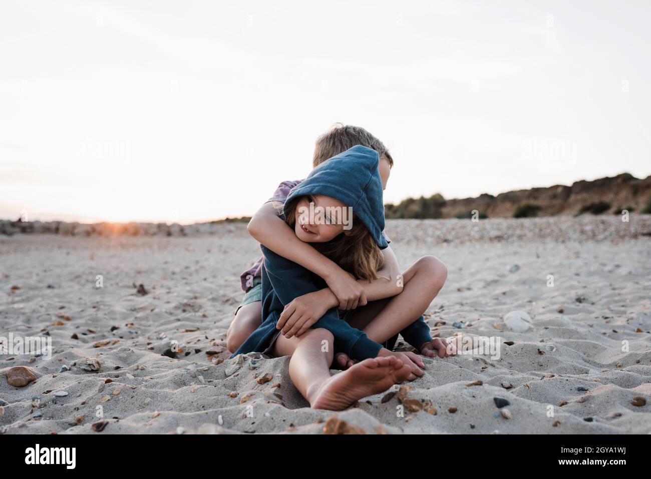fratello e sorella che abbraccia la spiaggia al tramonto Foto Stock