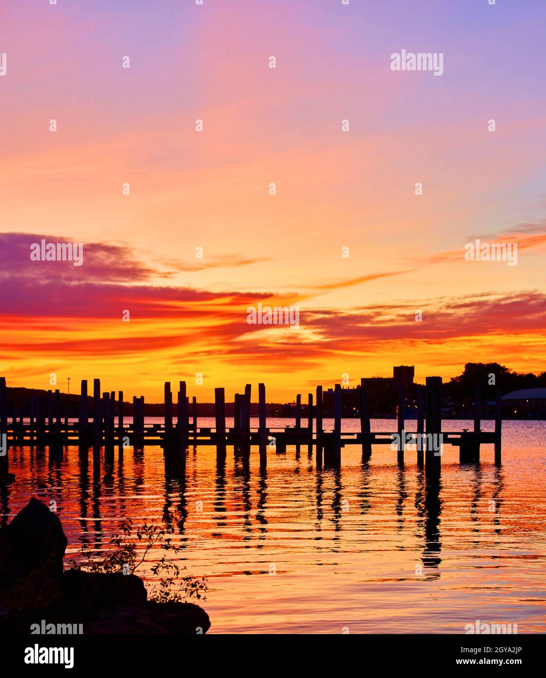 Panorama di un porto con silhouette di molo vuota e rosso arancio e porpora alba Foto Stock