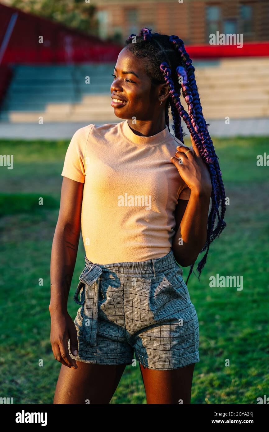 ragazza nera con trecce viola in posa in un parco Foto Stock