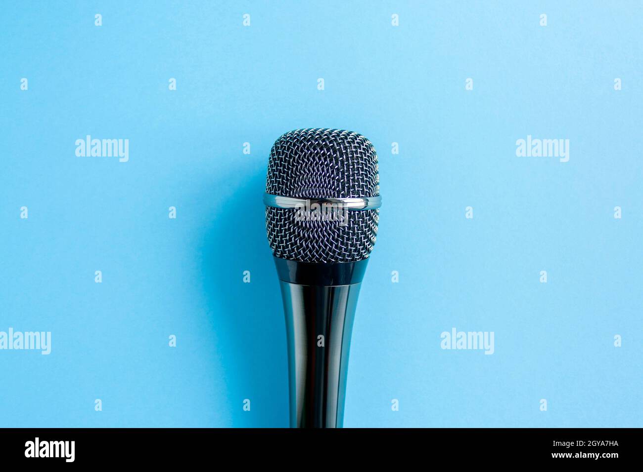 Microfono su sfondo blu colorato da vicino. Cantare, scrivere musica, karaoke online, creatività, concetto di voce, simbolo. Lezioni di canto Foto Stock