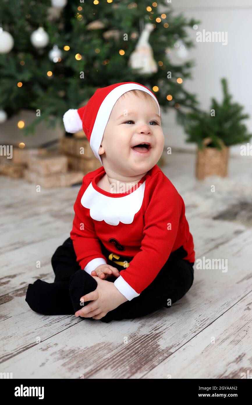 Bambino ragazzo in Babbo Natale Costume è seduto sul pavimento e ridendo Foto Stock