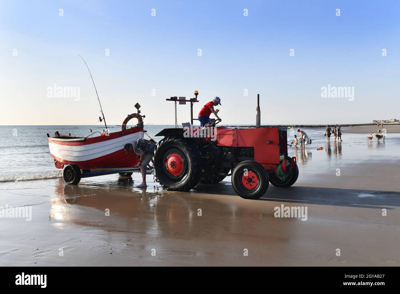 Ambleteuse spiaggia Cote d'Opale Francia settentrionale pescatore e ragazzo che traina la barca da pesca al mare con vecchio trattore. Foto Stock