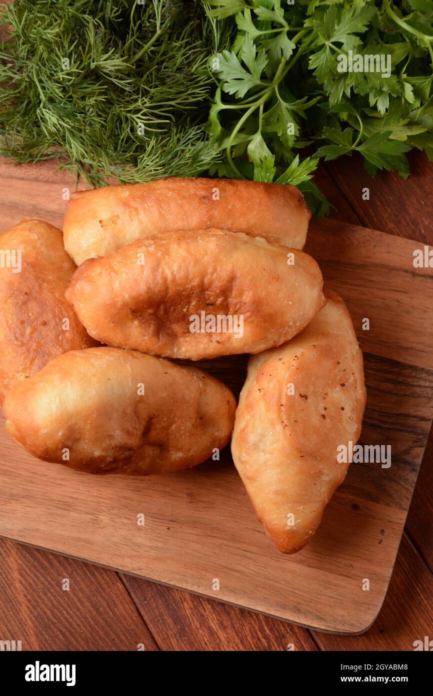 Pattuglie russe (Pasties, Hot Cakes, Pirozhki, Pies) su armadio di legno. Torte fritte tradizionali fatte in casa con patate Foto Stock