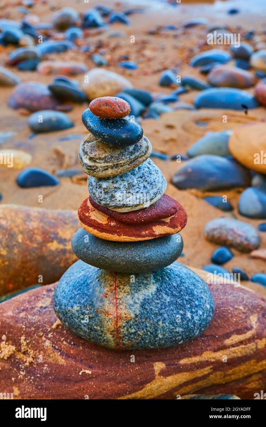 Cairn di pietra con pietre multicolore e una spiaggia arancione Foto Stock
